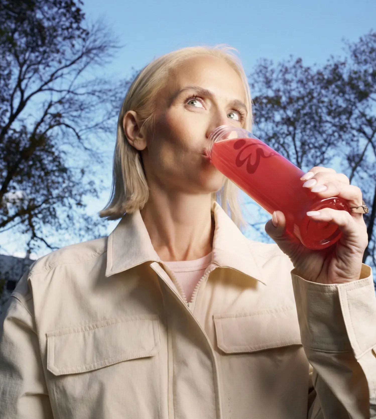 Woman drinking a red ByEla drink outdoors