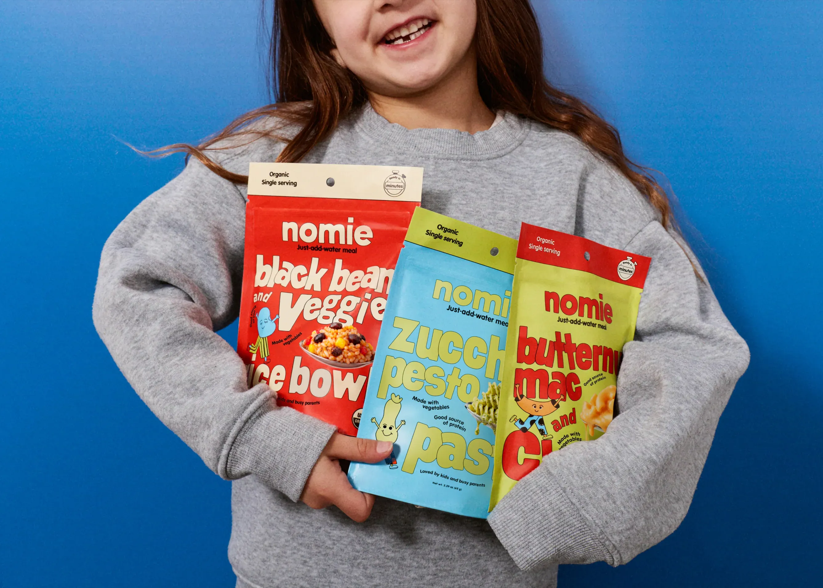 Girl holding three Nomie meal pouches