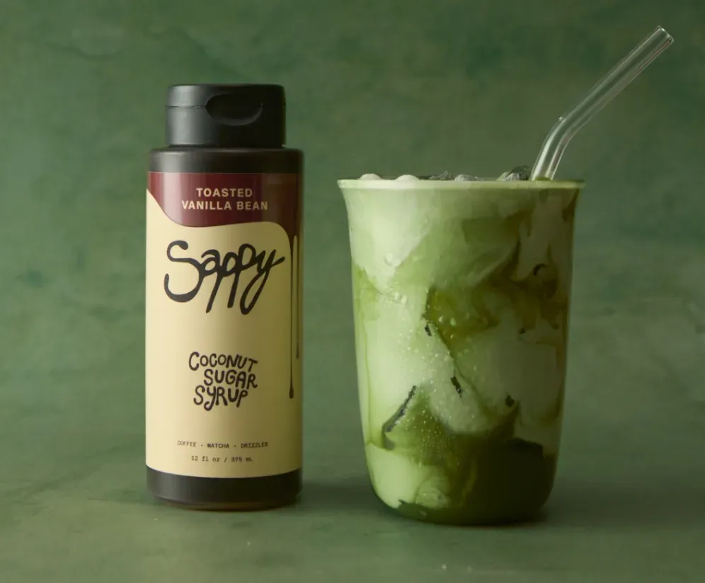 Sappy syrup bottle beside an iced matcha latte