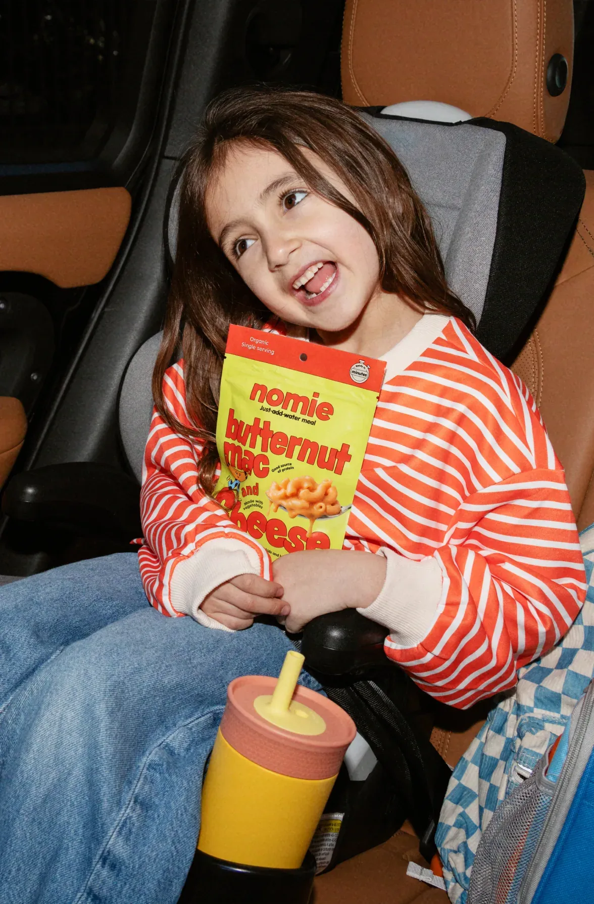 Girl in a car seat eating Nomie